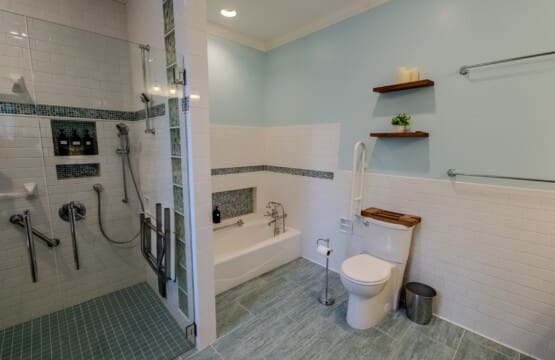 A spa-style en suite bathroom features dual vanities, a zero-entry shower, and thoughtful comfort for a relaxing stay.